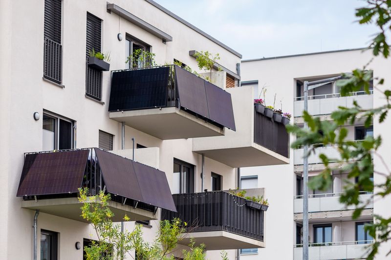 Einfamilienhaus mit mehreren Balkonen. Auf den Balkonen sind Balkonkraftwerke installiert. Man sieht noch mehrere Bäume.